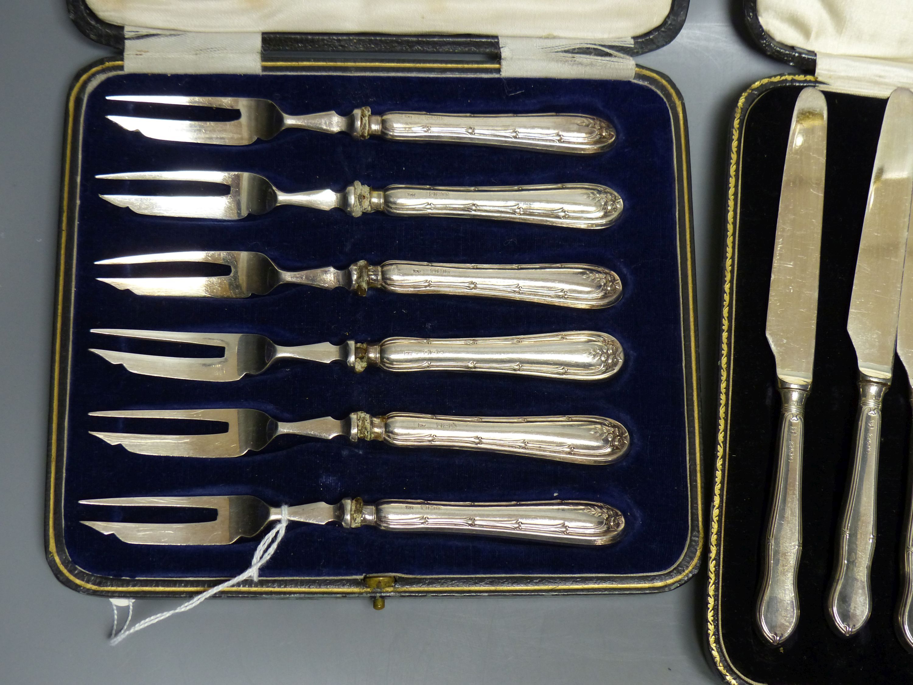 A cased set of twelve silver-handled dessert knives and a cased set of six similar cake forks (Sheffield 1919)